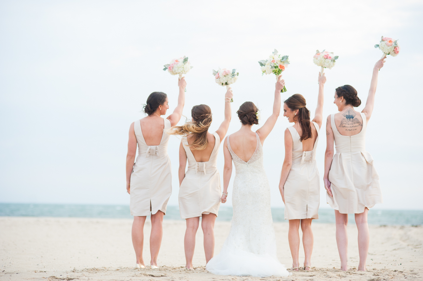 the ladies cheer and laugh at each other during wedding party pictures on the beach  