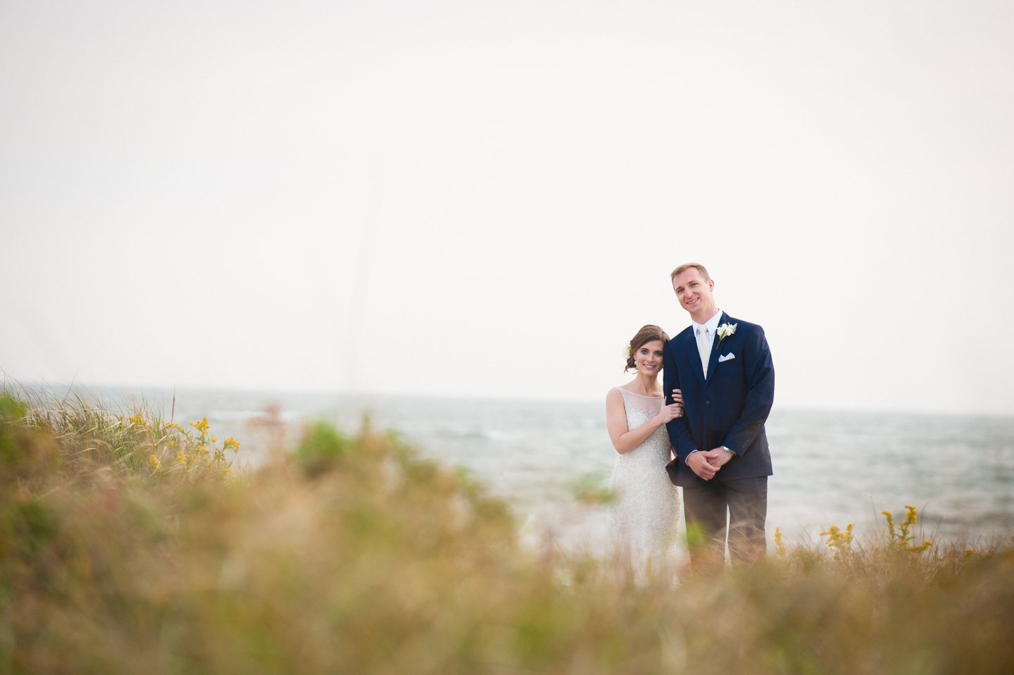 bride and groom stand side by side with sea grass and ocean all around 