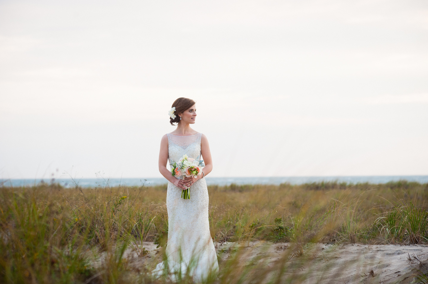 bride looks off in to the distance with the sea grass and ocean all around