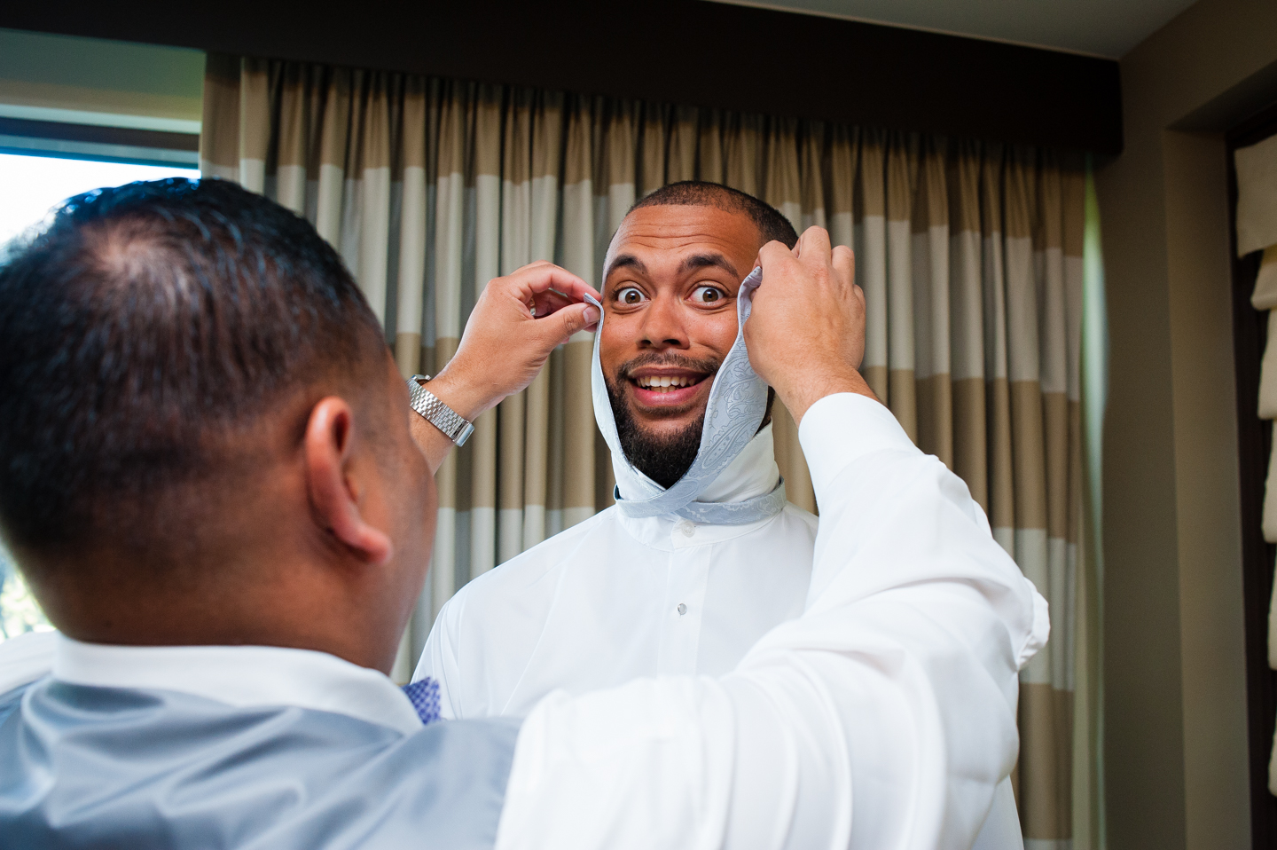 goofy groom getting help with his bowtie 