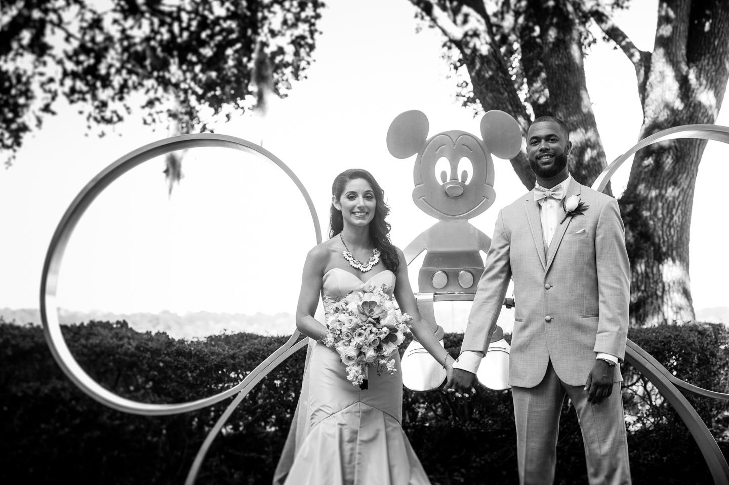 bride and groom pose with mickey mouse their disney world wedding 