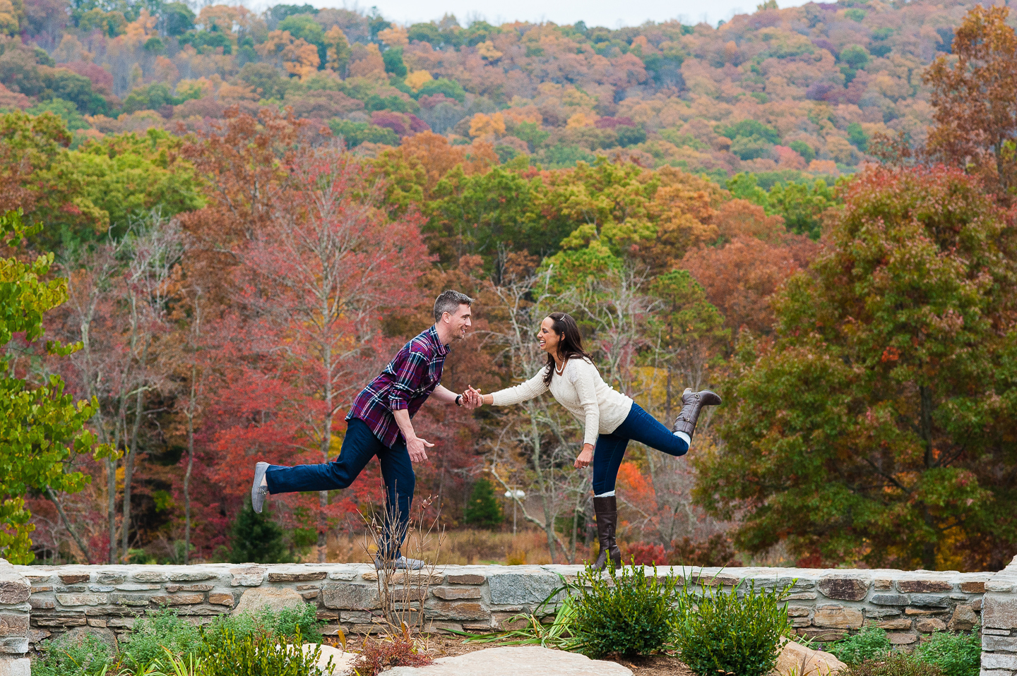 couple goofs off on wall at nc arboretum in asheville 