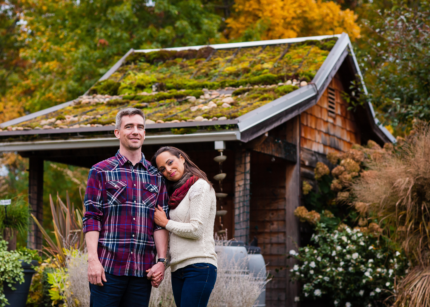 couple poses in front of beautiful building at nc arboretum