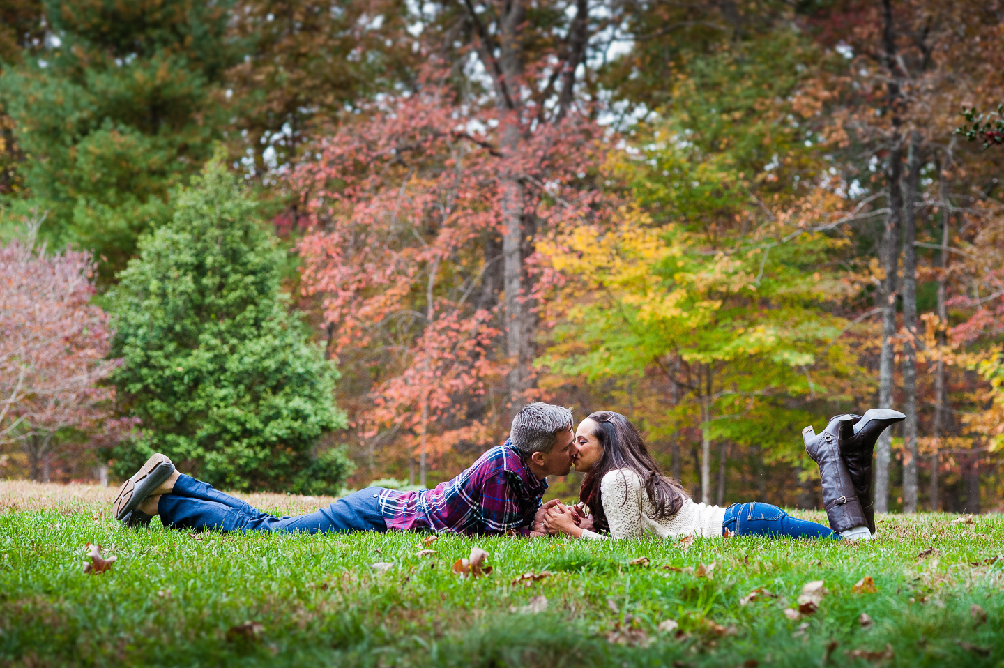 couple kiss in grass during fall asheville engagement session 