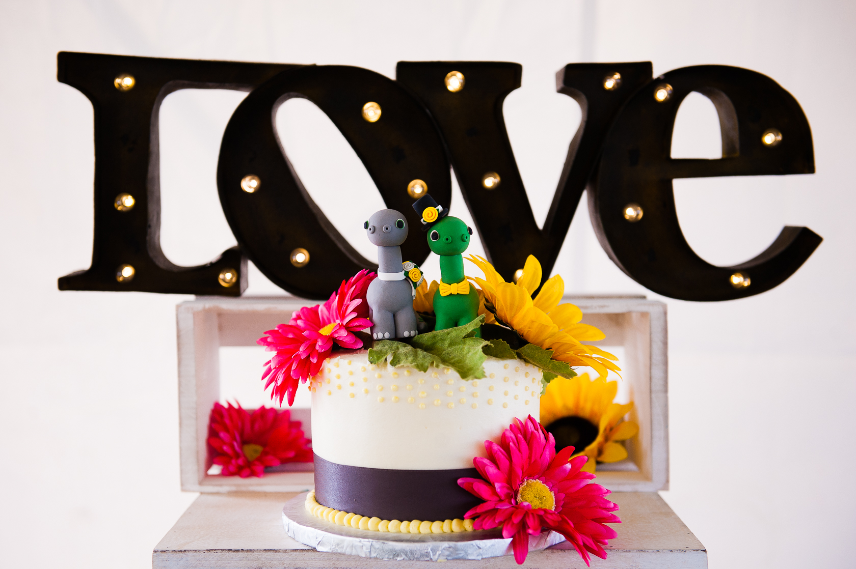 colorful wedding cake with dinosaur cake topper 