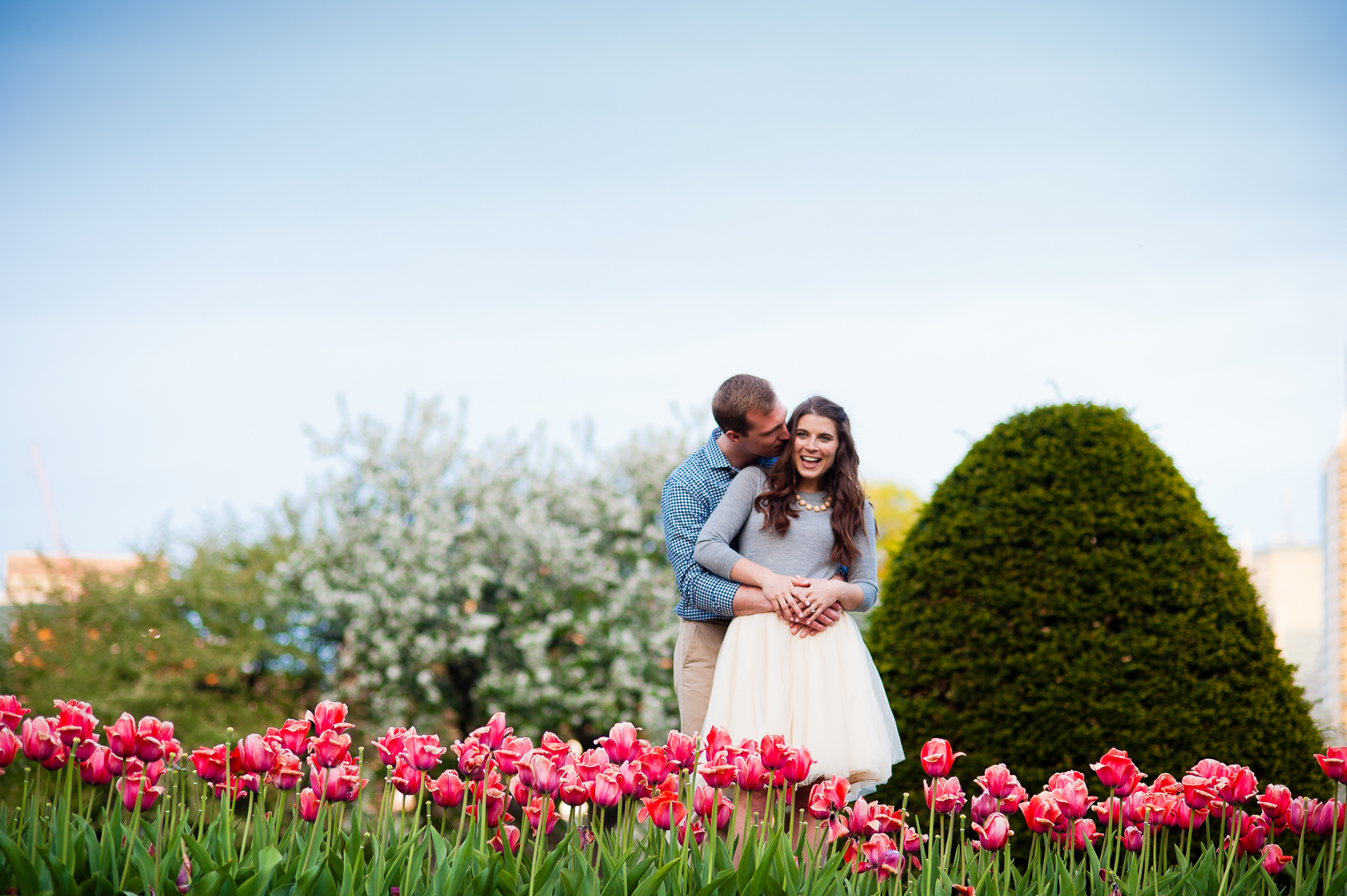 adorable couple poses in red tulips during their spring engagement session 