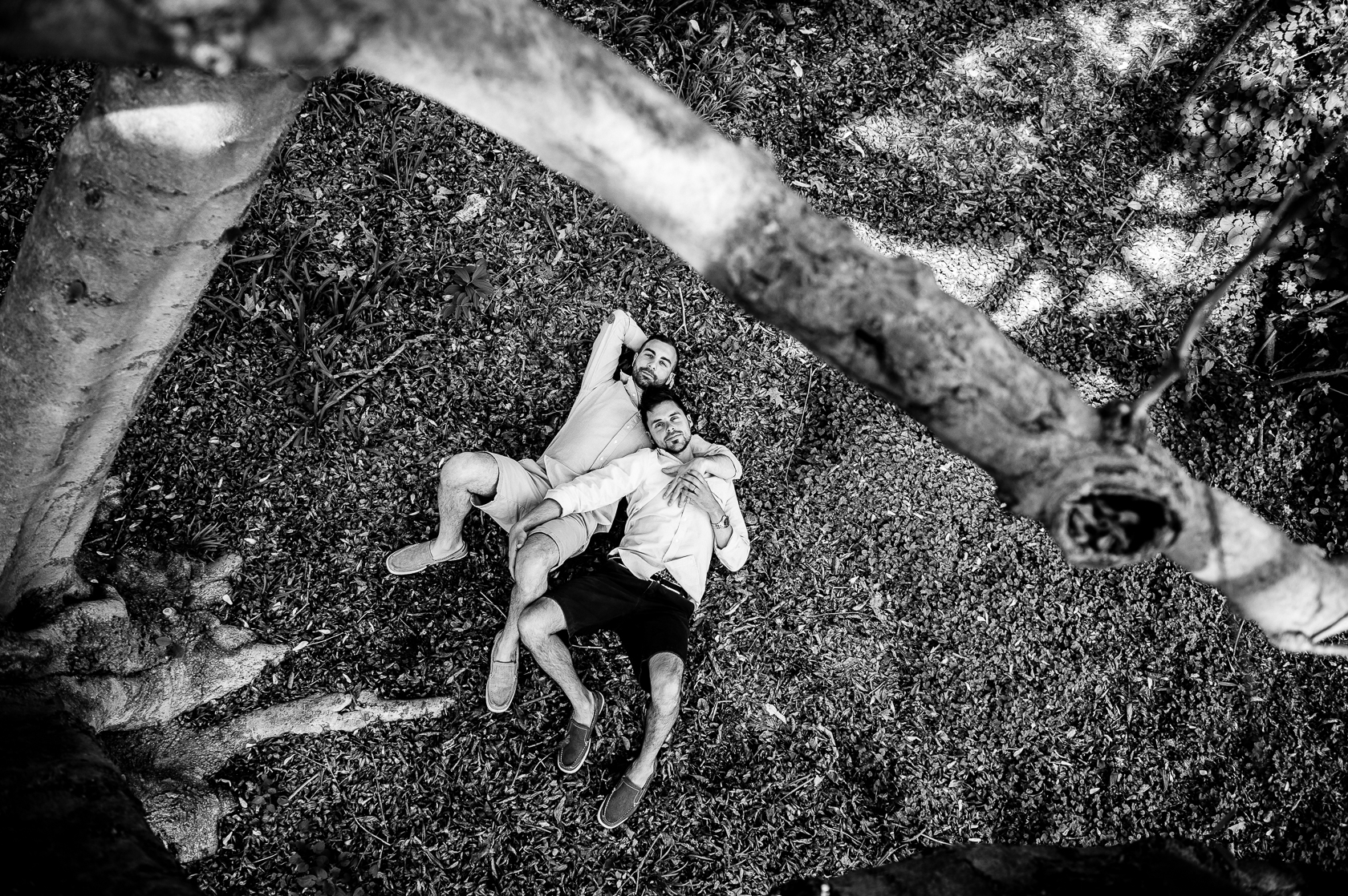 same sex engagement photo of guys cuddling under a tree