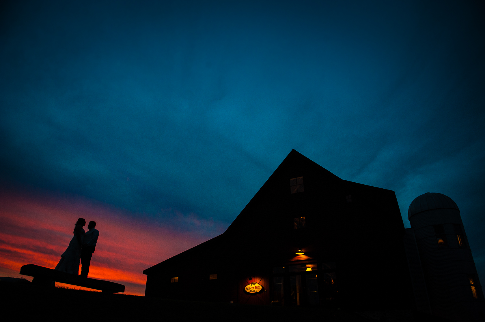 beautiful sunset silhouette of bride and groom during barn wedding 