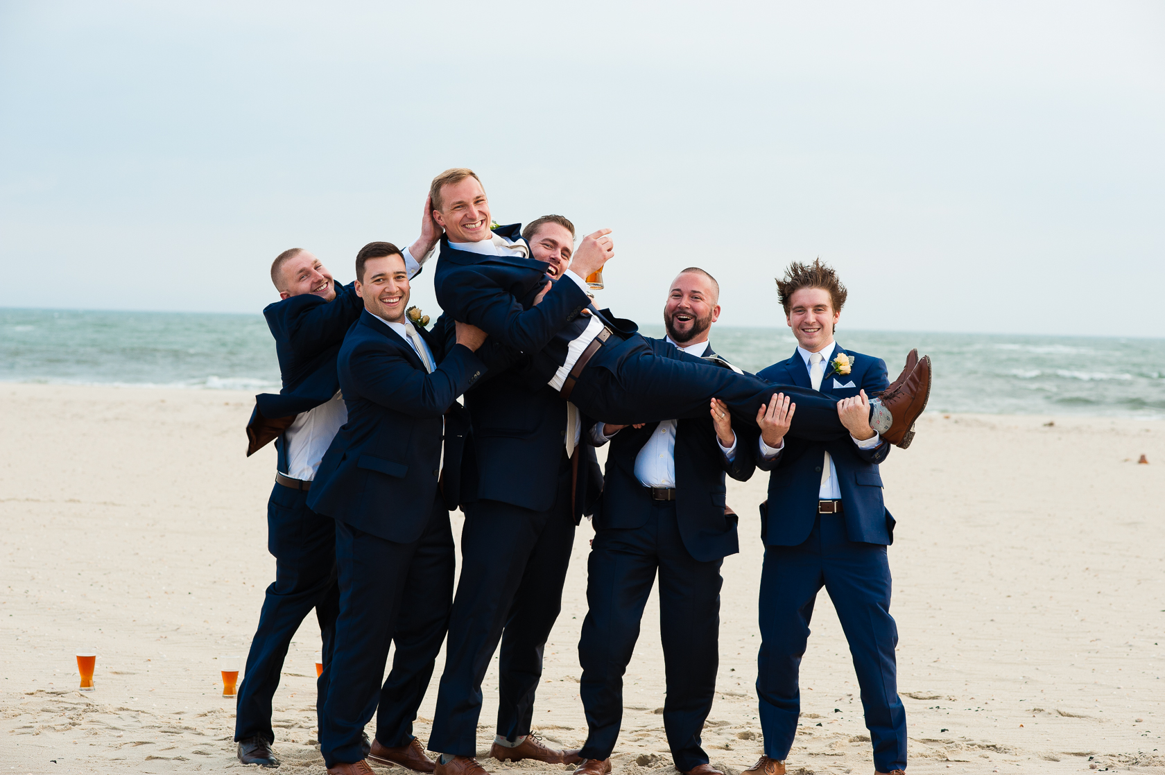 handsome groomsmen goofing off during beach  wedding 