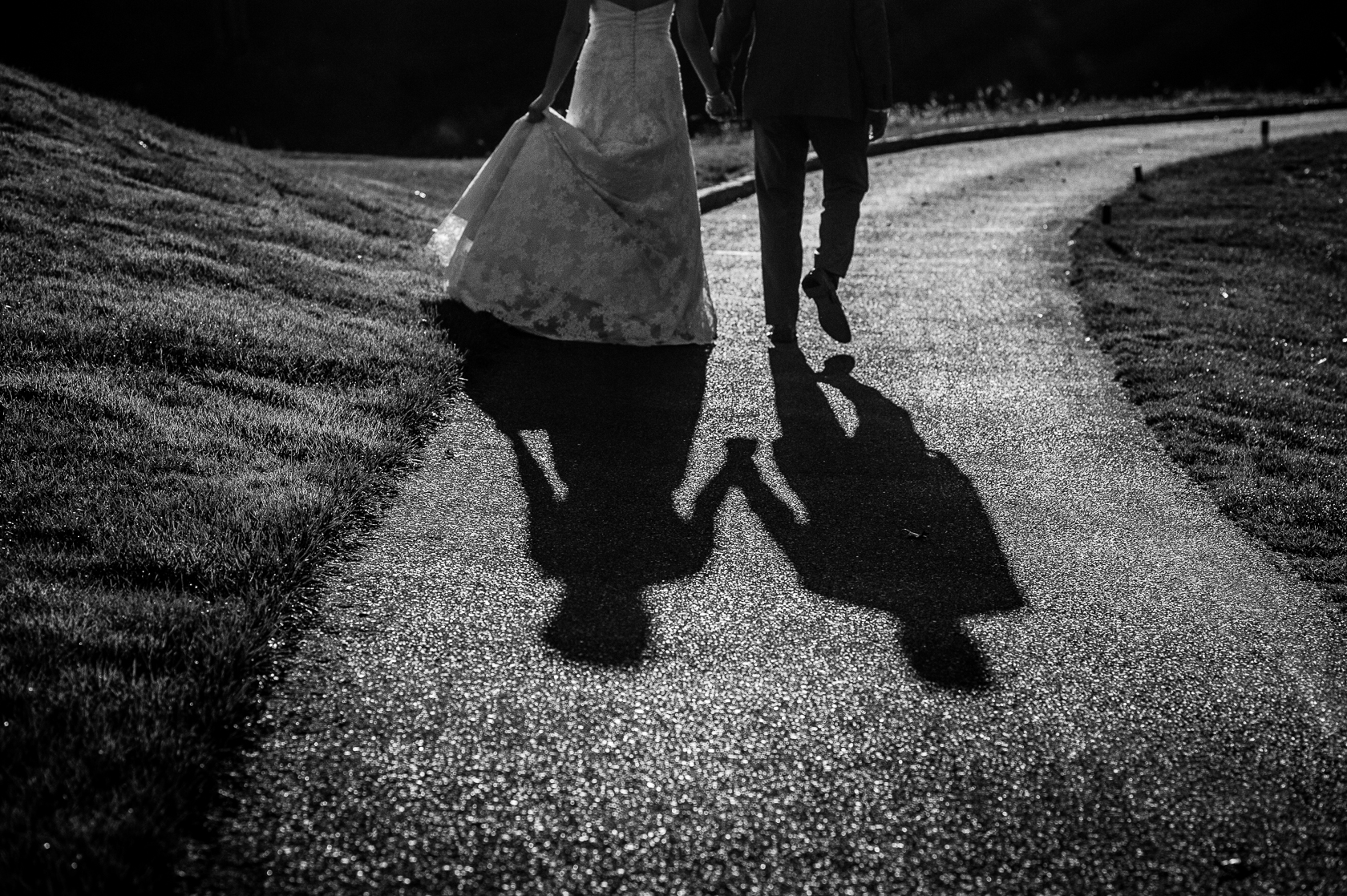 black and white shadow photograph of bride and groom holding hands 