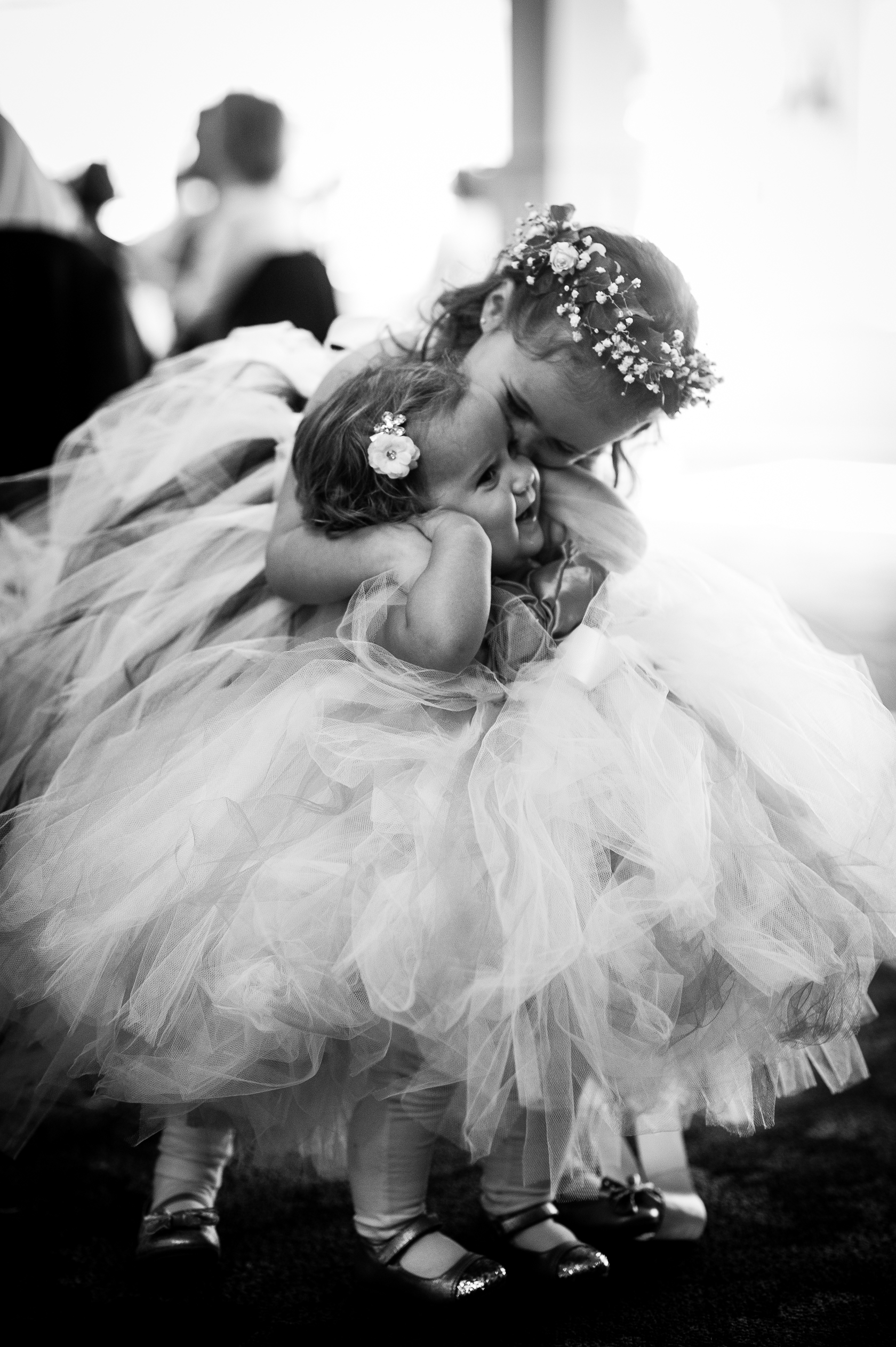 flower girl gives little sister a kiss on cheek 