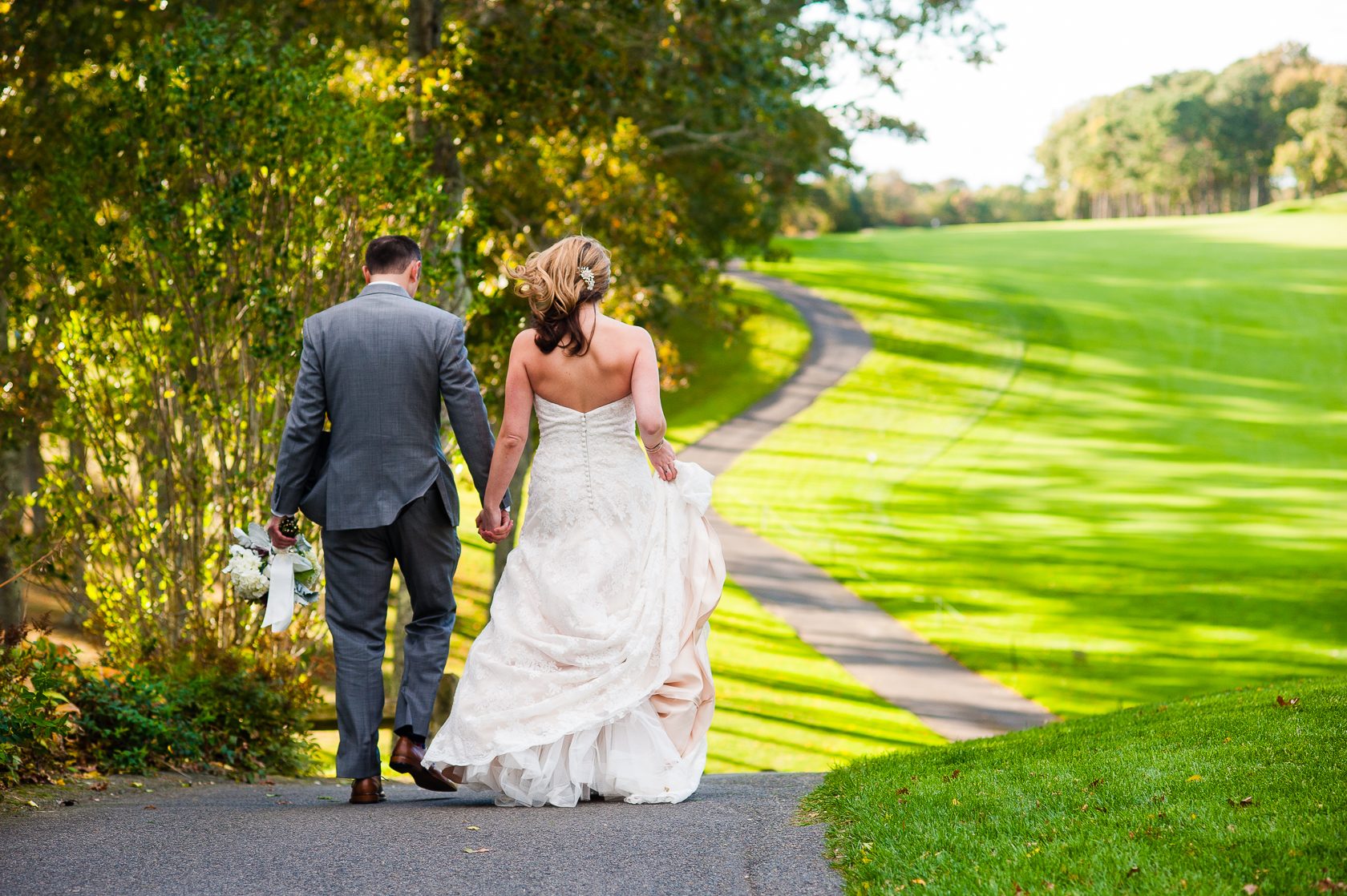 bride and groom walk on golf course path