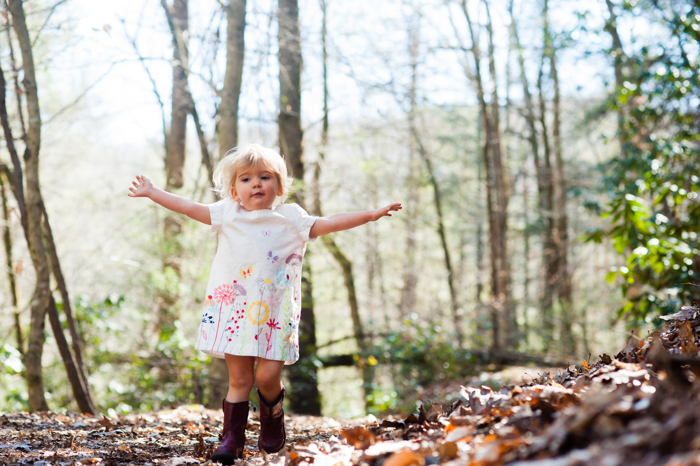 beautiful little girl runs down wooded path 