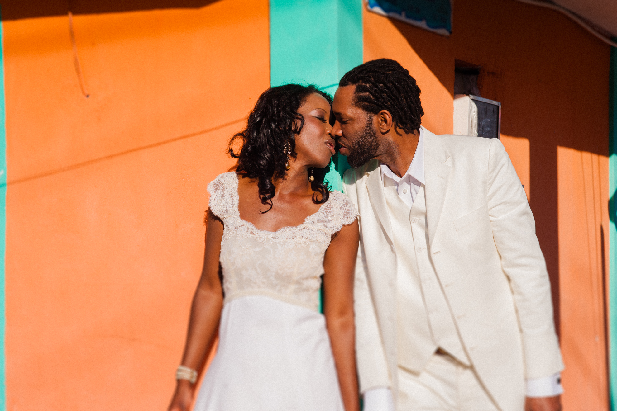 bride and groom kiss in front of colorful building on Isla Mujeres