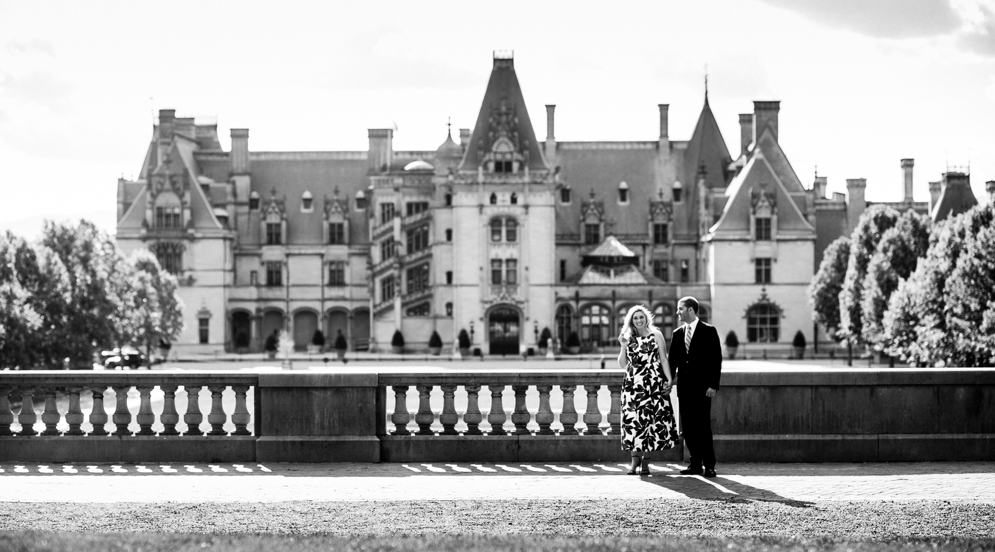 engaged couple poses for engagement photo in front of Biltmore Mansion 