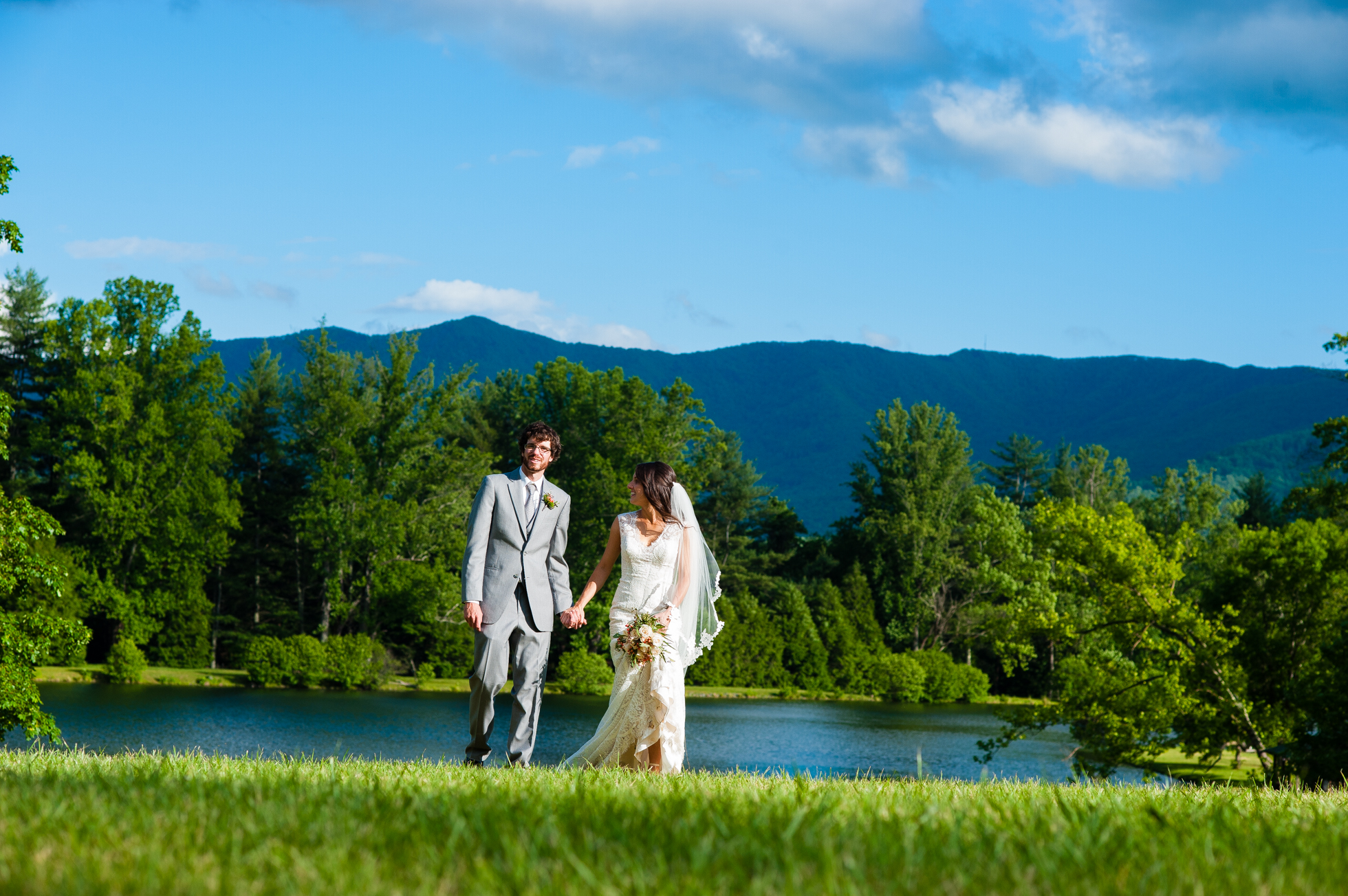 bride and groom walking through meadow at lake eden 