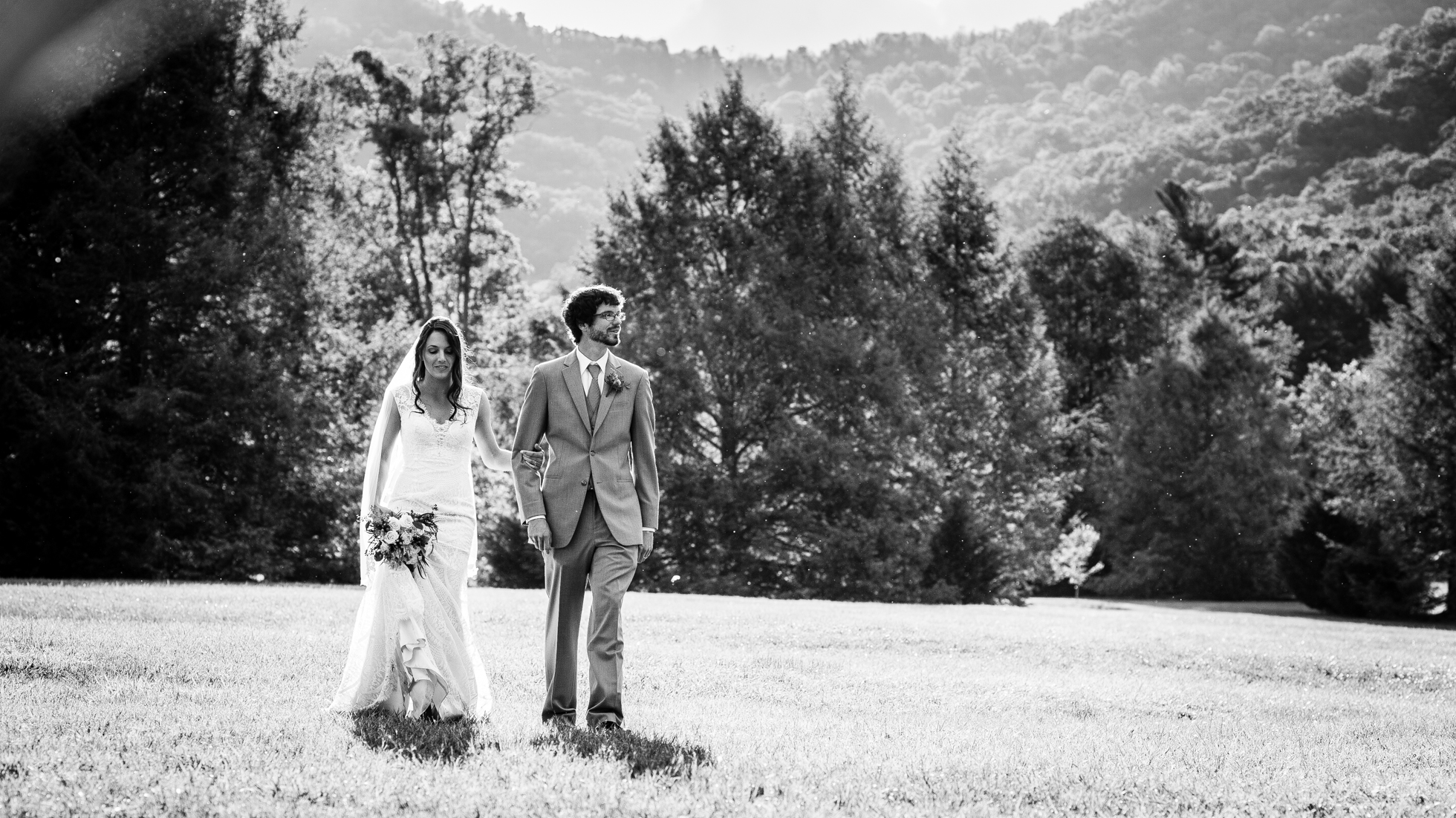 bride and groom walk through meadow at Lake Eden