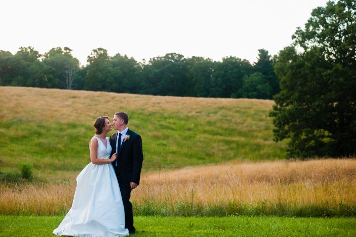 bride and groom pose in field on biltmore estate during their wedding