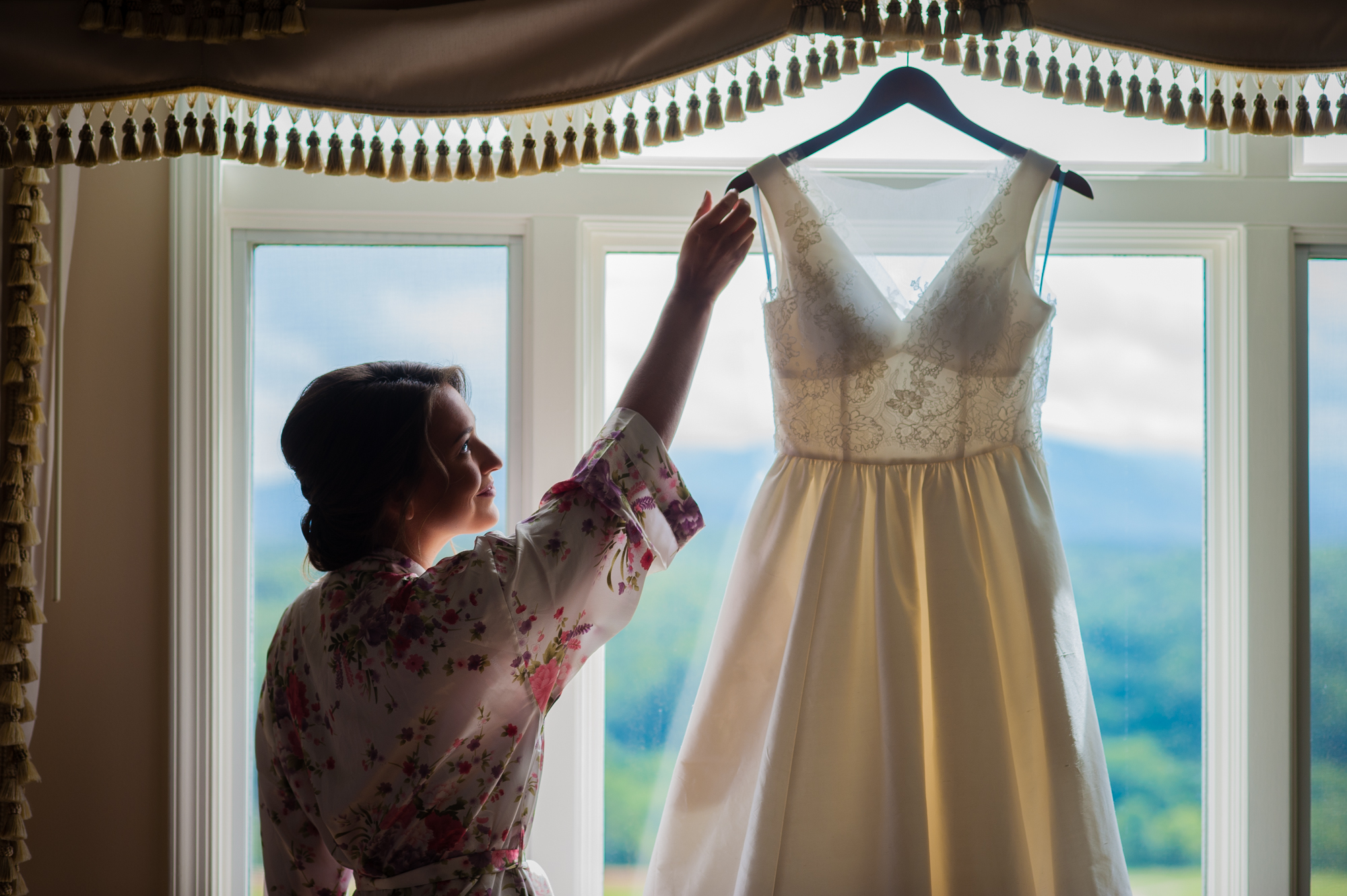 bride getting her dress down from a window 