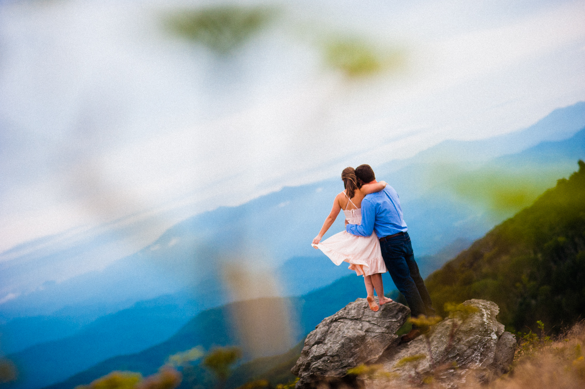 engaged couple looks out at mountains 