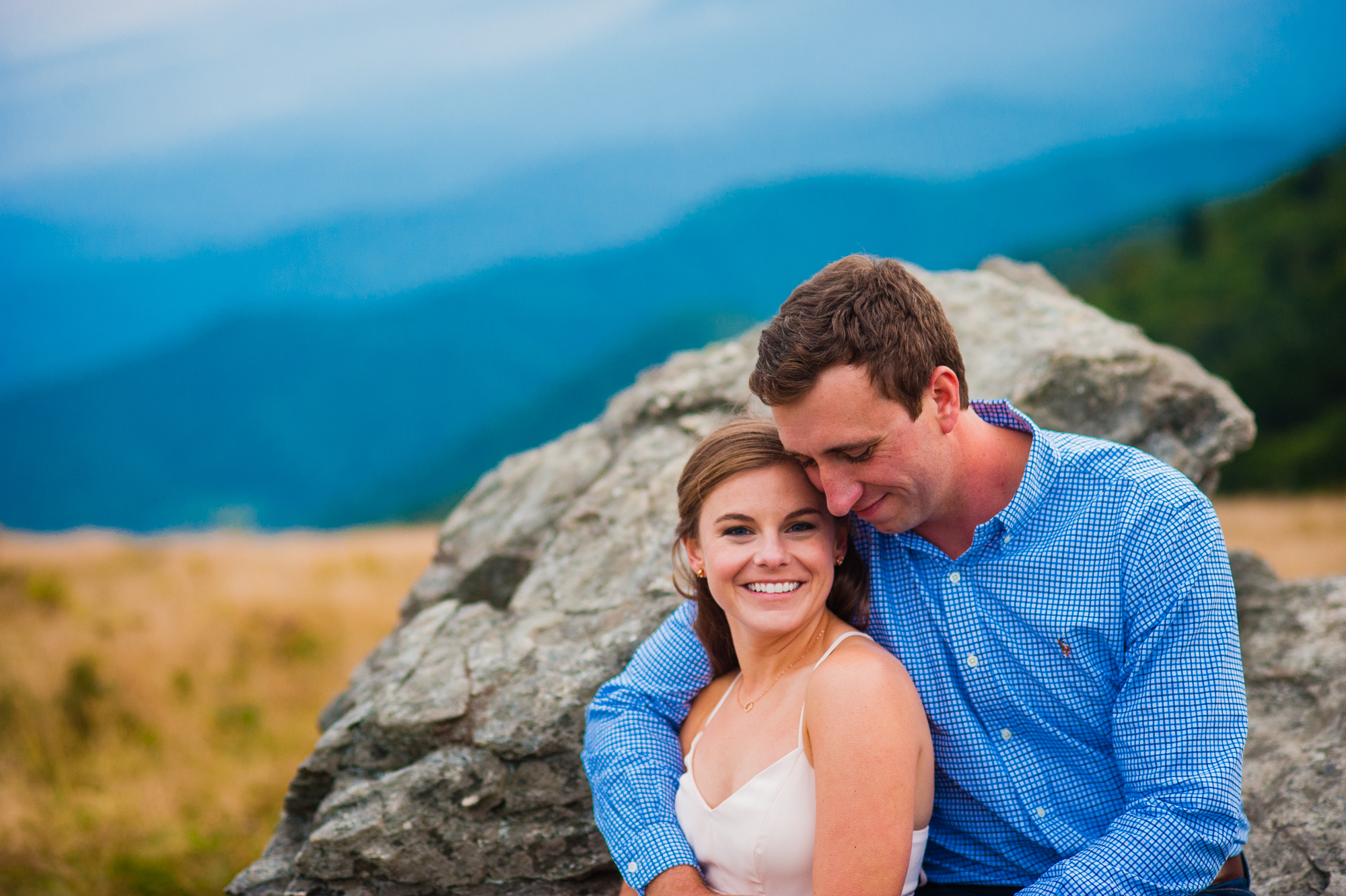 couple sits together during engagement session in the mountains