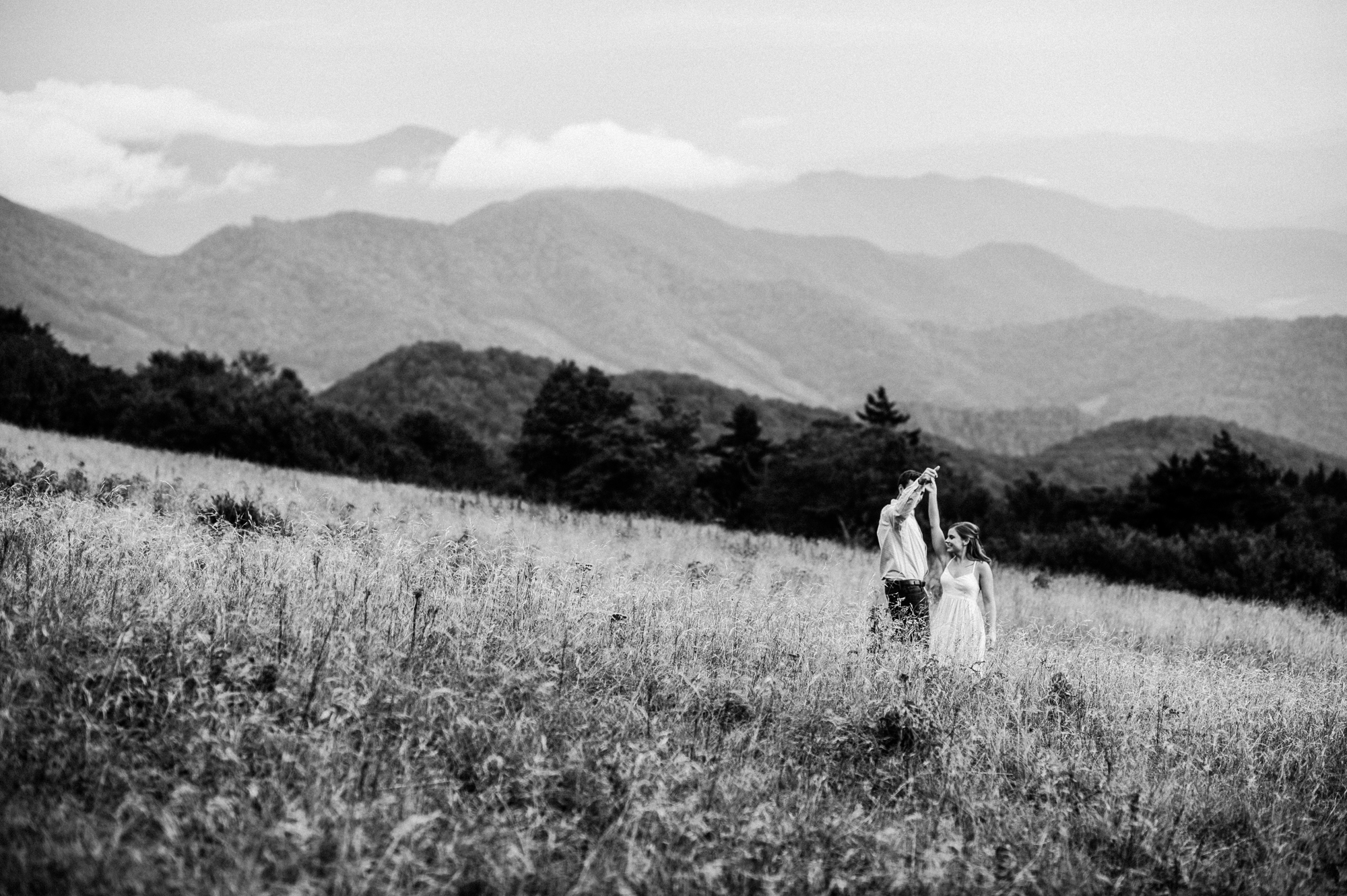 couple dancing on a mountain top during their engagement session 