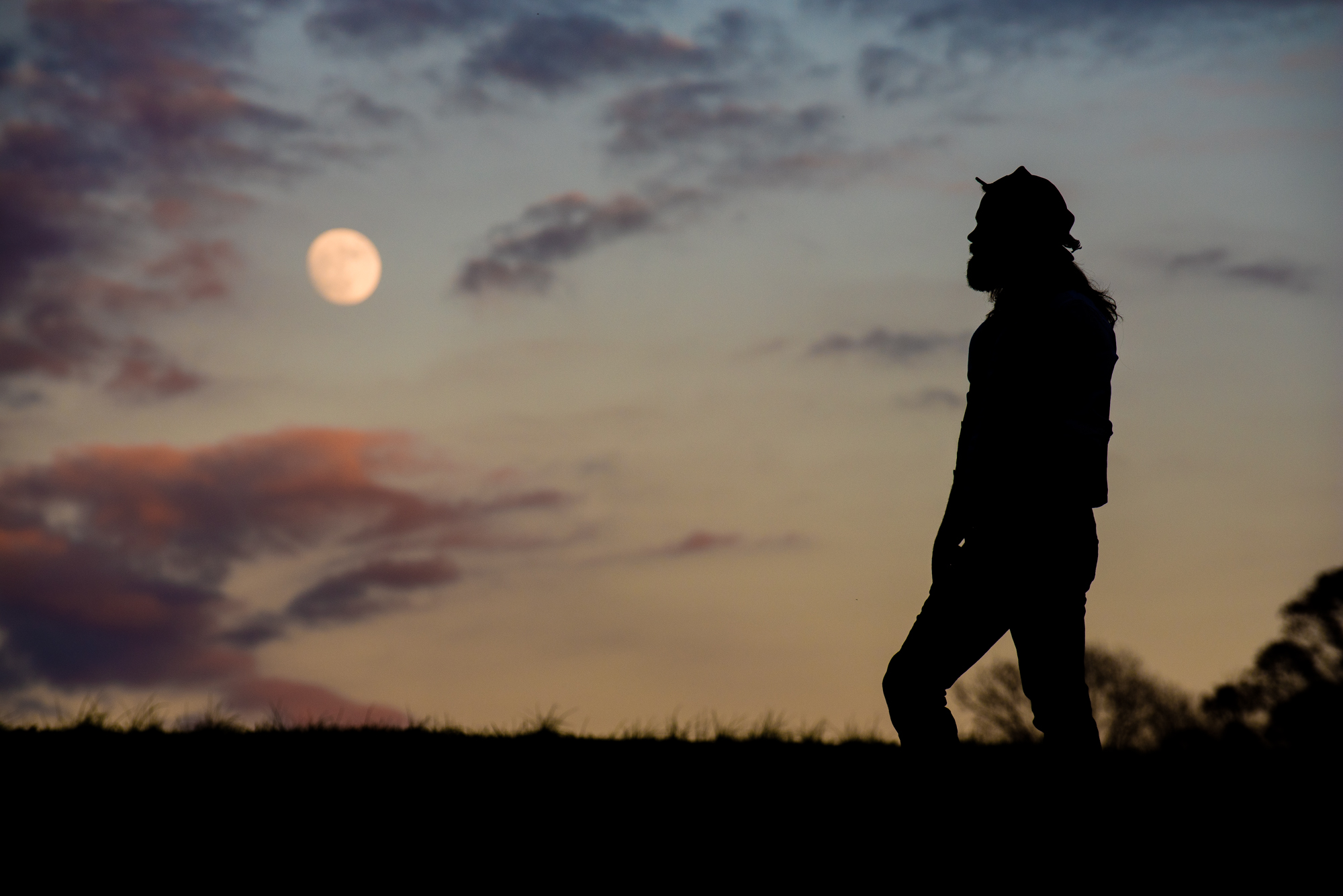 silhouette of man on mountain with the moon