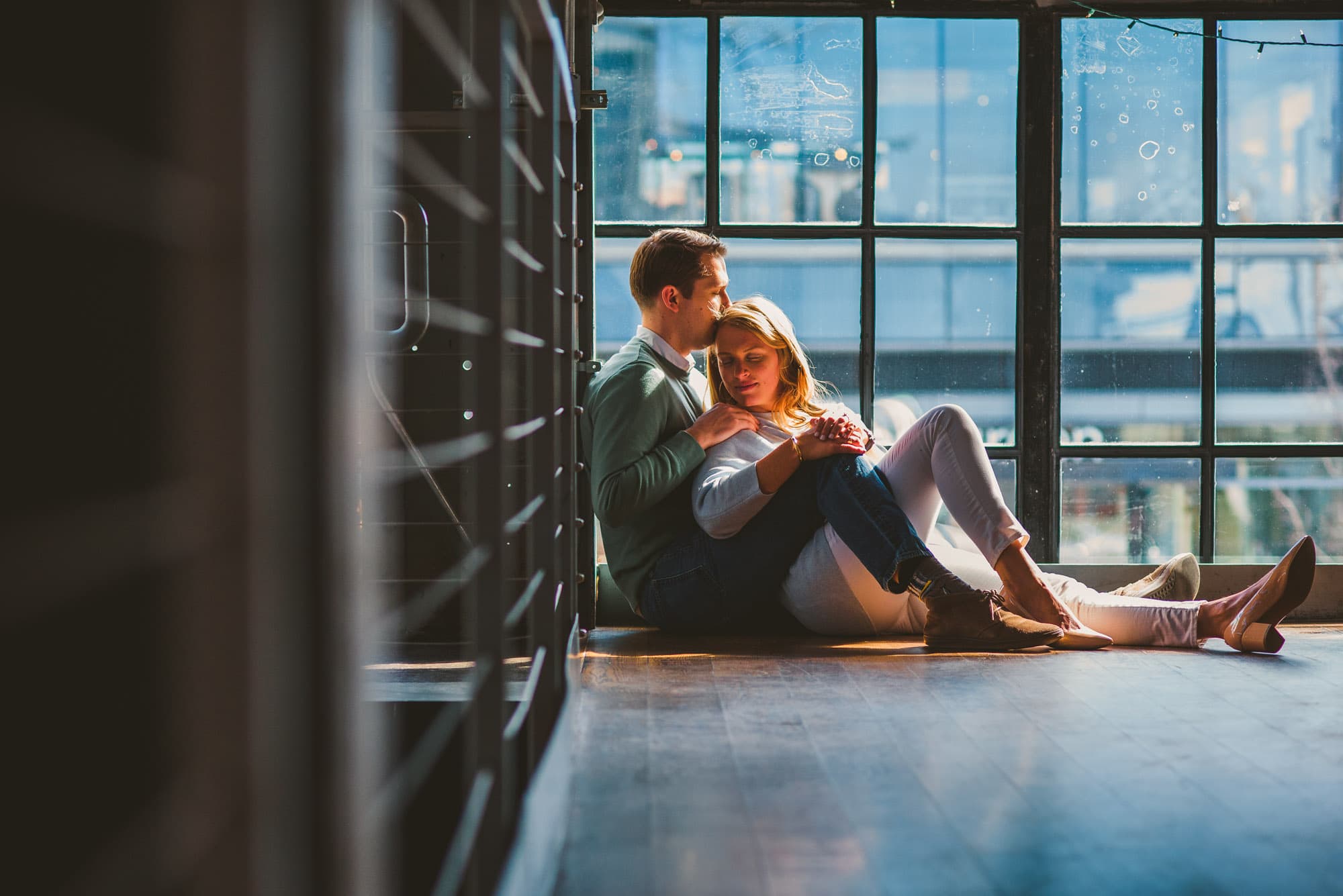 couple cuddling on the floor during their brewery engagement session 