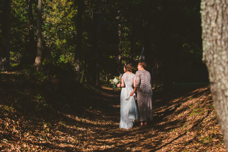 Mom and a bride walk the tree lined lane up to the ceremony site at Yesterday Spaces