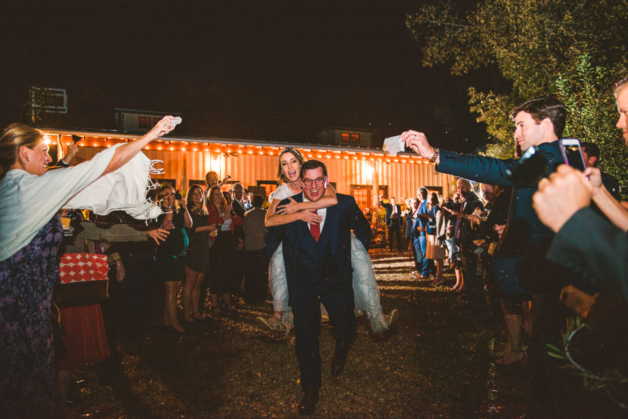 a fun piggyback getaway by bride and groom after their wedding reception in Asheville