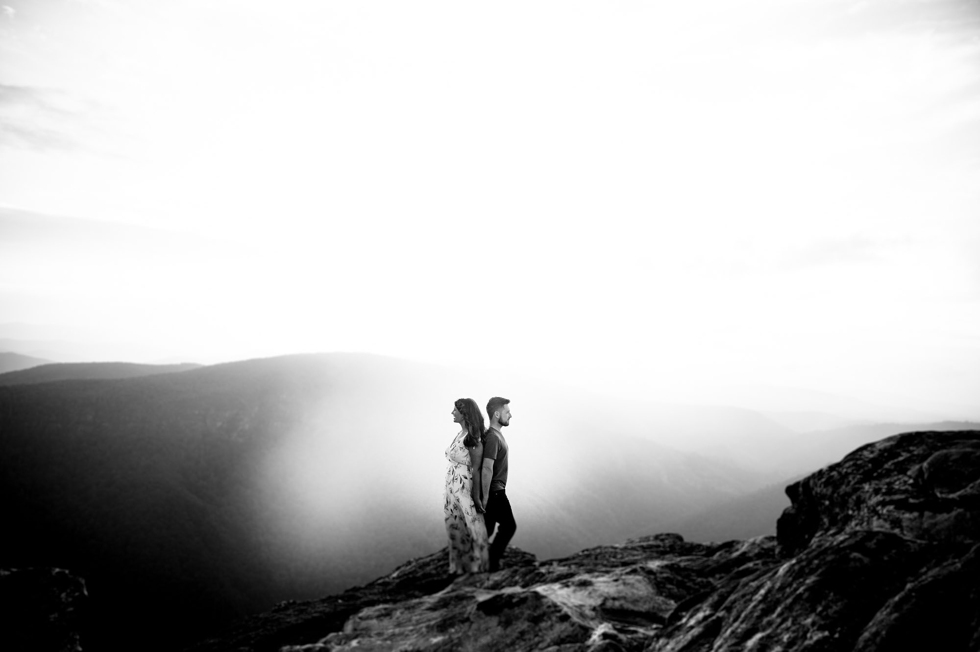 Couple stands back to back during their mountain engagement session 