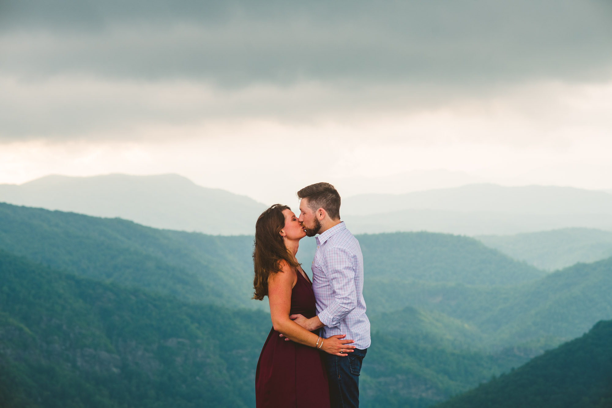 Couple kisses on a mountaintop during their adventure mountain engagement 