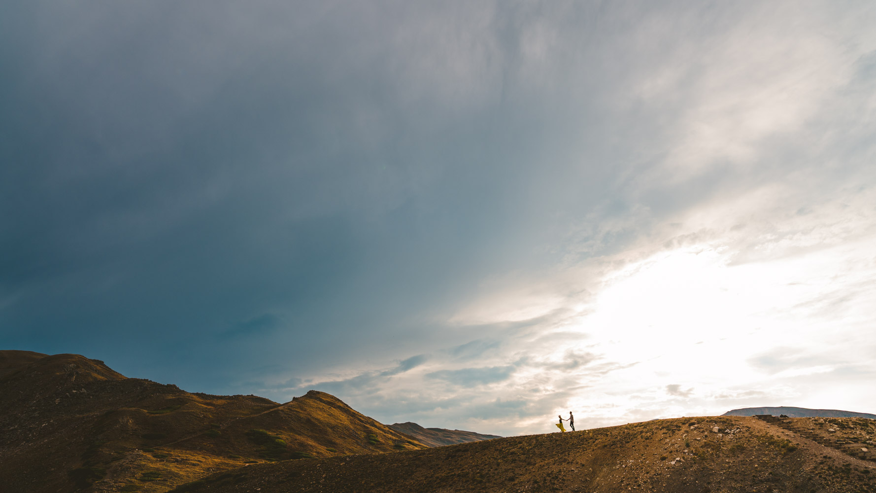 Loveland Pass elopement photograph of couple running across the mountain ridge