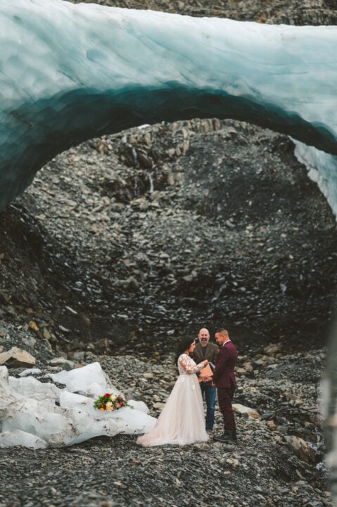 bride and groom during alaska glacier wedding near ice arch 